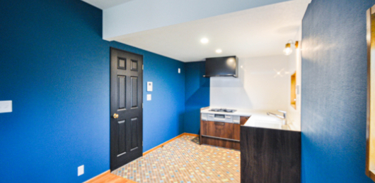 キッチンのある場所はタイルで仕切りながら、壁を青色で統一させたスタイリッシュな空間。